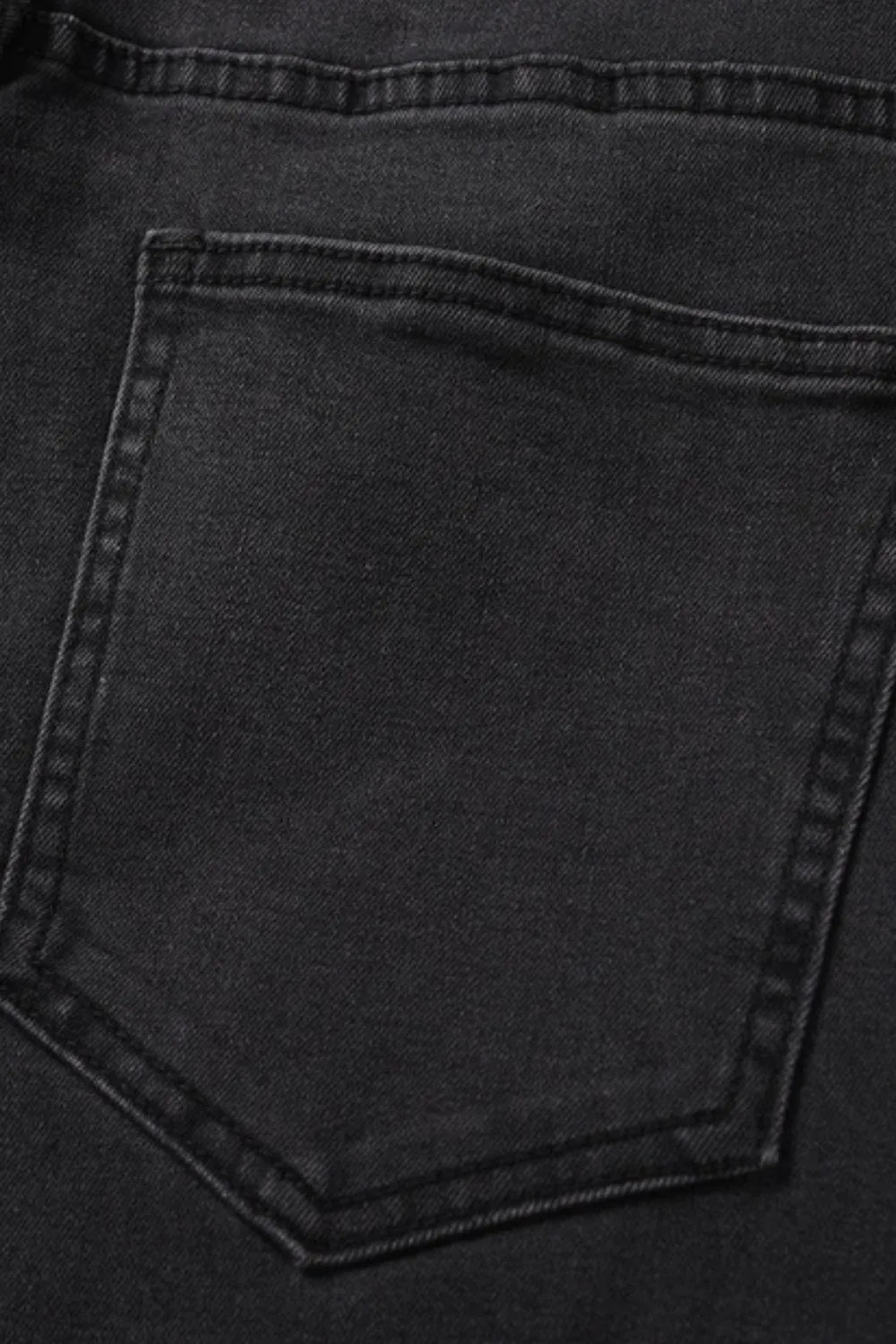 Black wash denim jeans with split hem detail, close-up of back pocket.