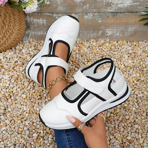 White Mary Jane cutout sneakers with black contrast trim and adjustable strap.