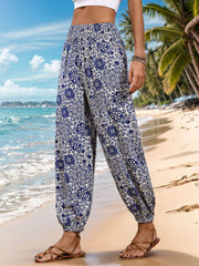 Bohemian harem trousers in dusty blue with a medallion print and elastic waist, styled with sandals.