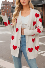 Beige acrylic knit cardigan with red heart appliqués and buttons.