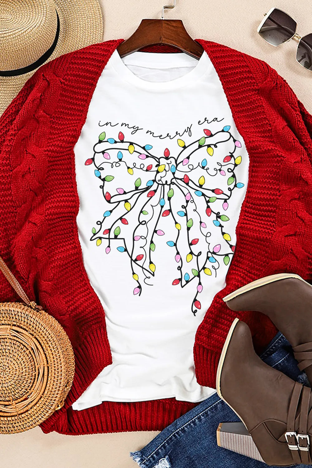 White t-shirt with a colorful holiday light bow graphic and "in my merry era" text.