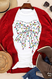 White t-shirt with a colorful holiday light bow graphic and "in my merry era" text.