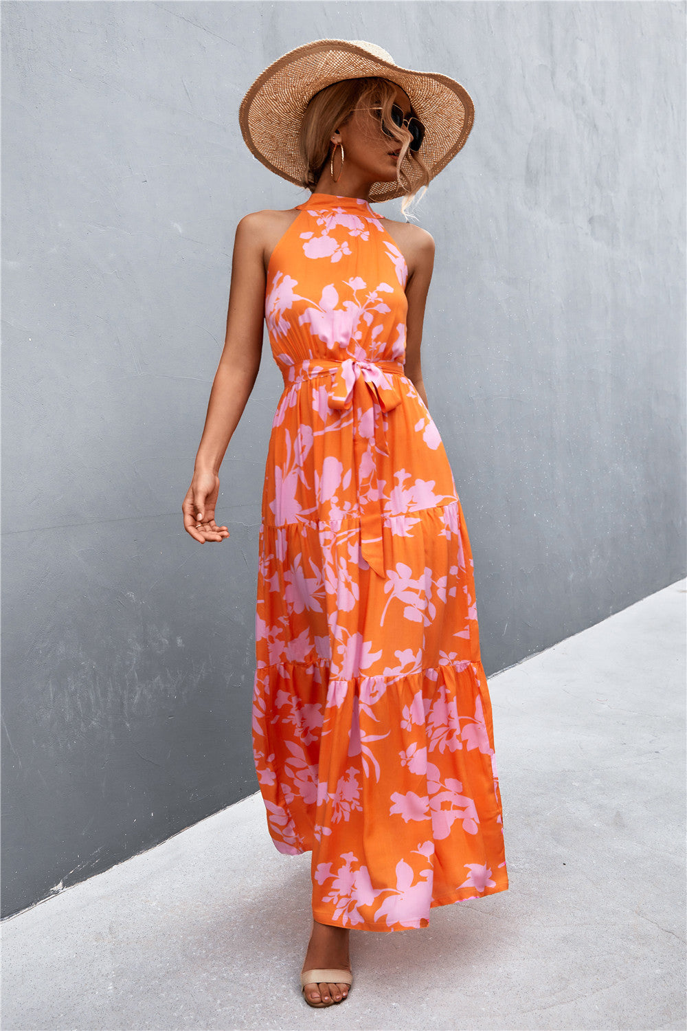 Orange floral print maxi dress with halter neckline and tiered skirt.