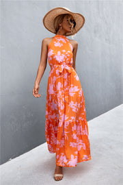Orange floral print maxi dress with halter neckline and tiered skirt.