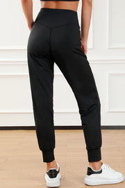 Black joggers with a high waist and cuffed ankles, styled with white sneakers.