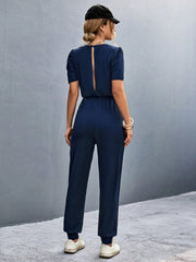 Dark blue jumpsuit with puffed short sleeves and back cutout detail.