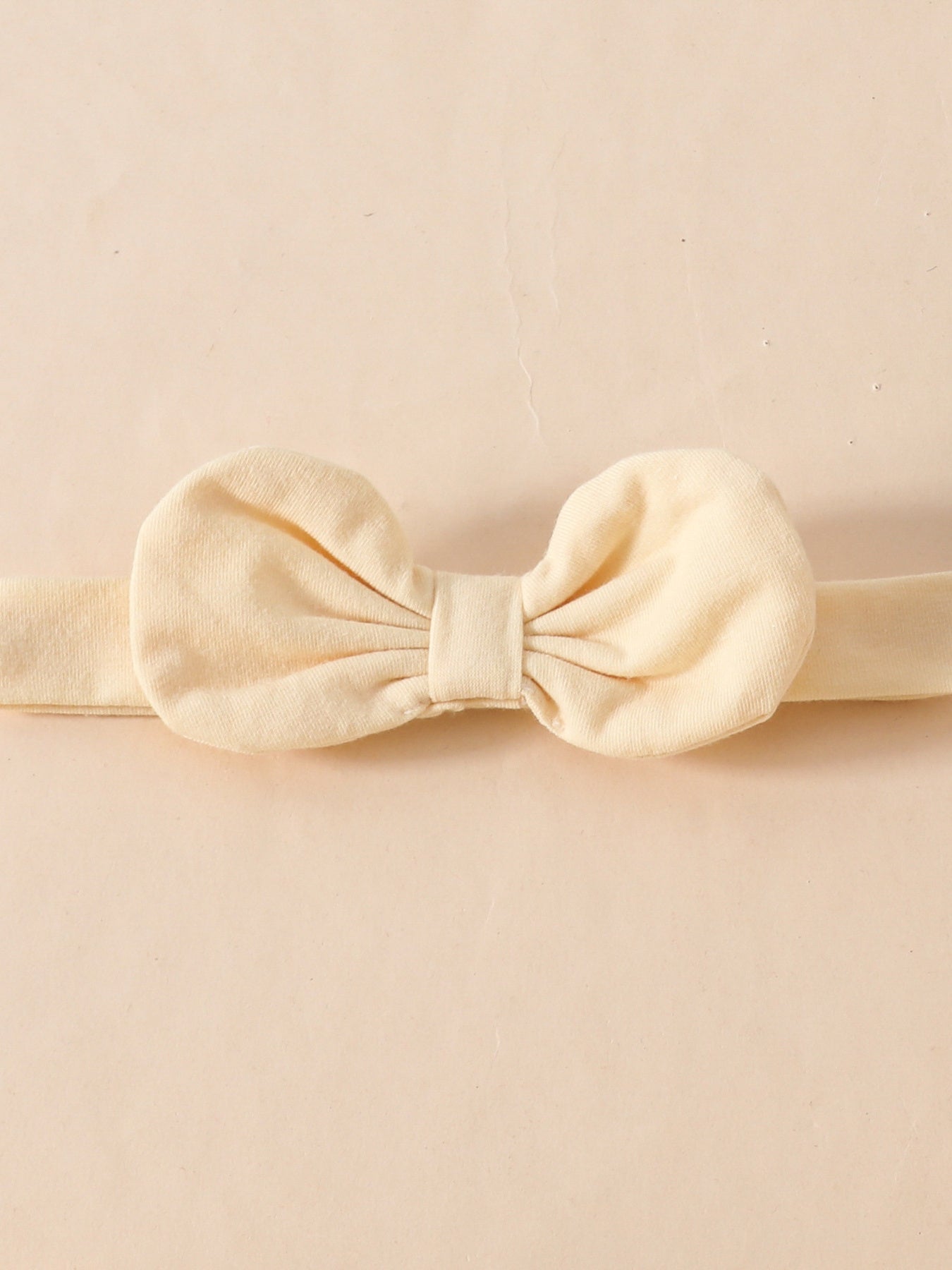 Cream baby headband with a large fabric bow detail