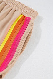 Tan sweatpants with colorful retro stripes on the side and elastic waistband.