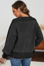 Black textured knit cardigan with waffle weave and ribbed hem.