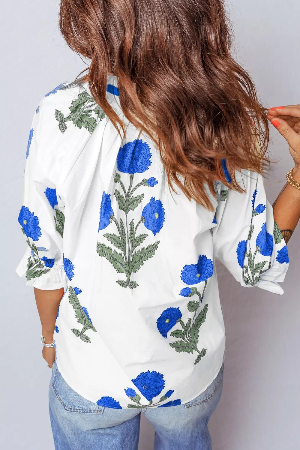 White cotton blouse with blue floral print and ruffled sleeves.