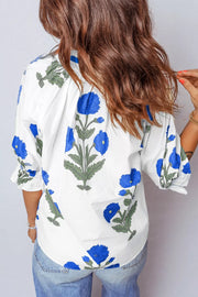 White cotton blouse with blue floral print and ruffled sleeves.