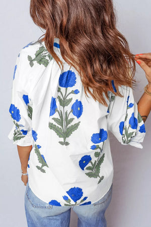 White cotton blouse with blue floral print and ruffled sleeves.