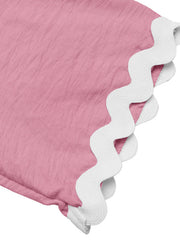 Pink maternity romper cover-up with white scalloped trim detail.