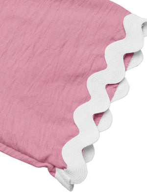 Pink maternity romper cover-up with white scalloped trim detail.