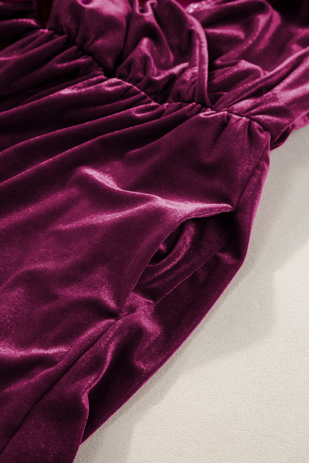 Burgundy velvet wrap romper with ruffled detail and side pockets.