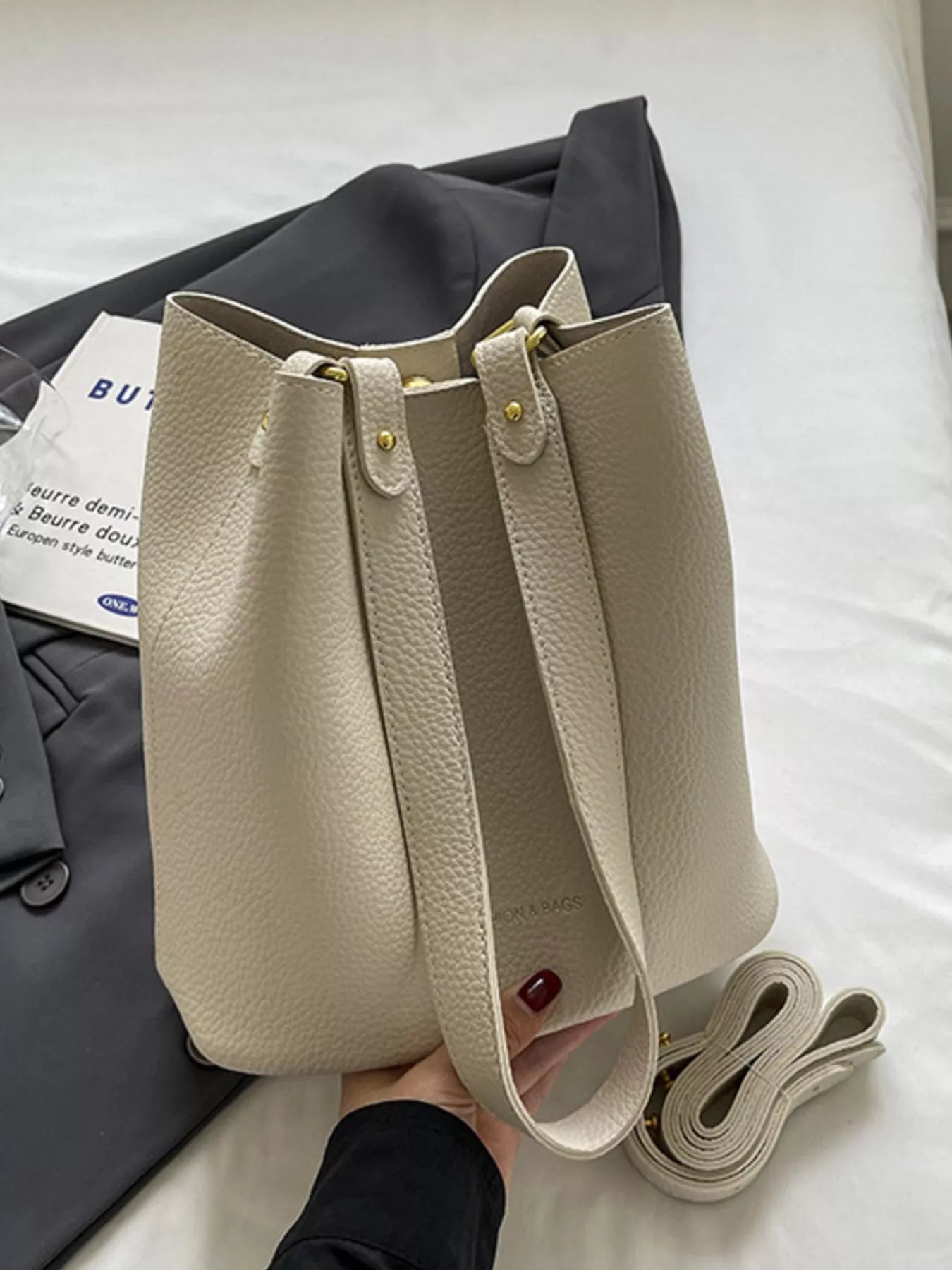 Off-white pebbled leather mini tote bag with gold hardware and adjustable strap.