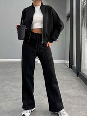 Black bomber jacket and wide-leg tracksuit with drawstring waist and front zipper detail.
