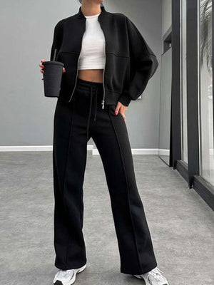 Black bomber jacket and wide-leg tracksuit with drawstring waist and front zipper detail.
