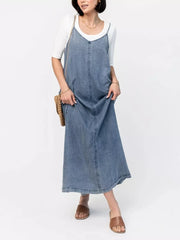 Light blue denim maxi dress with V-neck and adjustable straps, worn over a white tee.