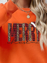 Orange graphic sweatshirt with "Merry Christmas" text in buffalo plaid and leopard print.