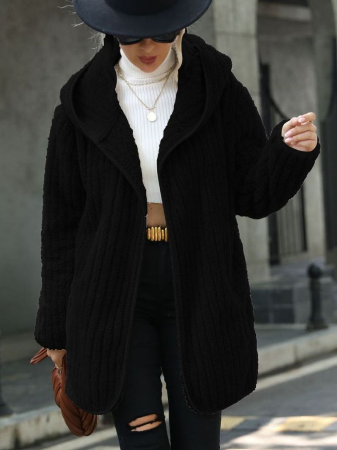 Black textured teddy hooded open coat with a relaxed fit, styled with a white turtleneck and ripped jeans.