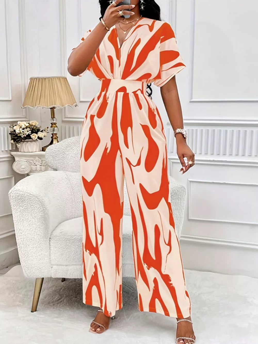 Orange and cream abstract print wide-leg romper with short sleeves and a V-neck.