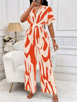 Orange and cream abstract print wide-leg romper with short sleeves and a V-neck.