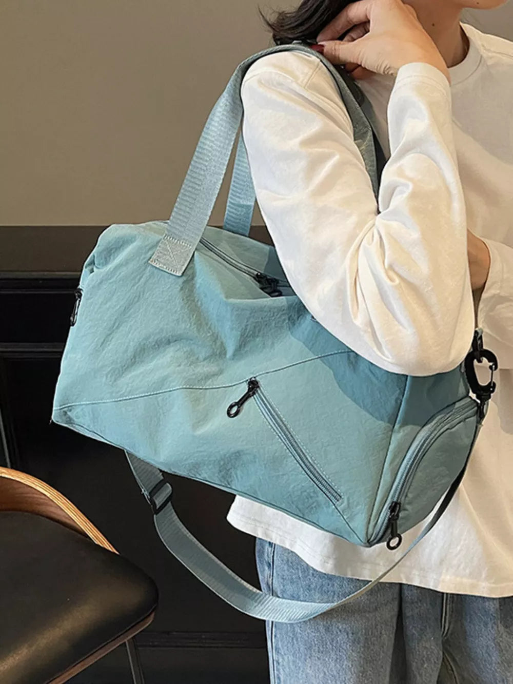 Light blue nylon travel duffel bag with multiple zippered pockets and adjustable strap.
