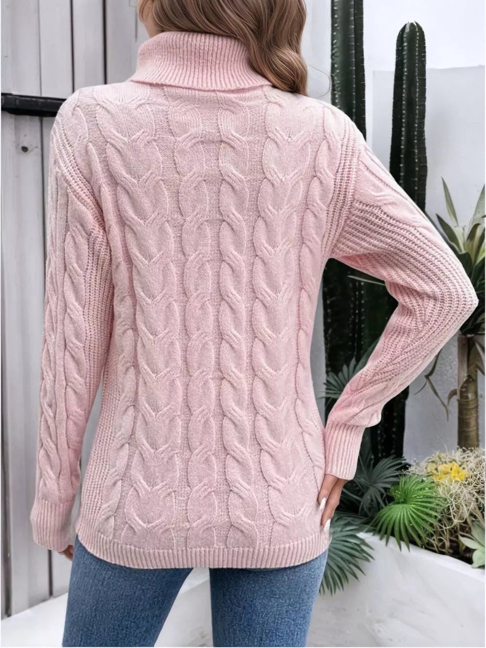Pink cable-knit turtleneck sweater with ribbed cuffs and hem.