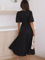 Black midi dress with puff sleeves, cinched waist, and tiered skirt.