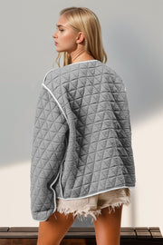 Gray diamond quilted jacket with white piping and a bow closure detail.