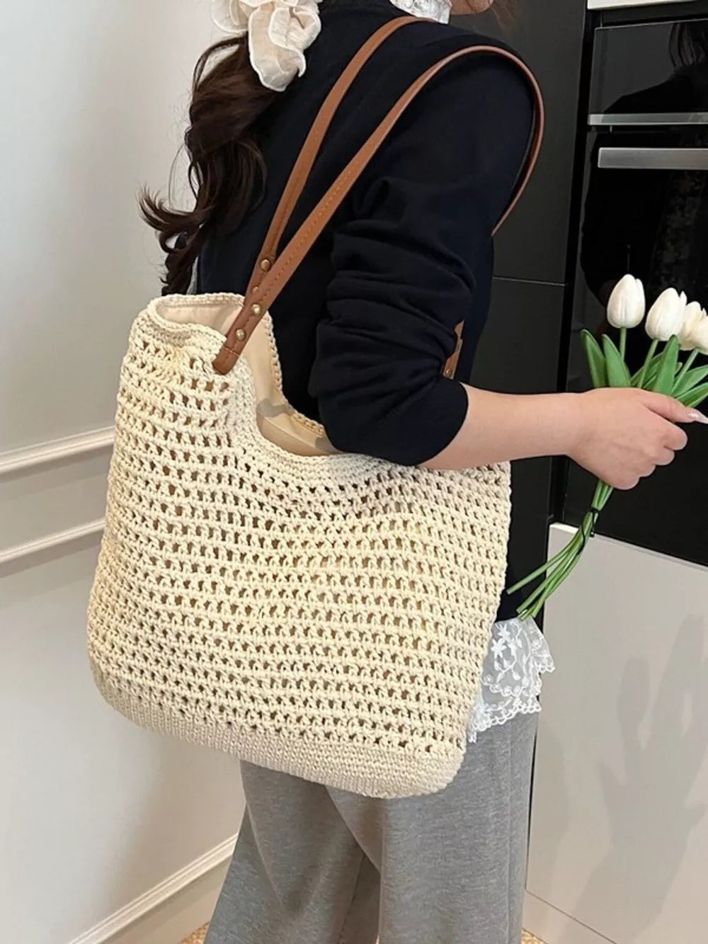 Beige woven straw shoulder bag with leather straps, open knit detail