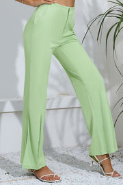 Neon green tailored trousers with a split hem detail and a flared leg.