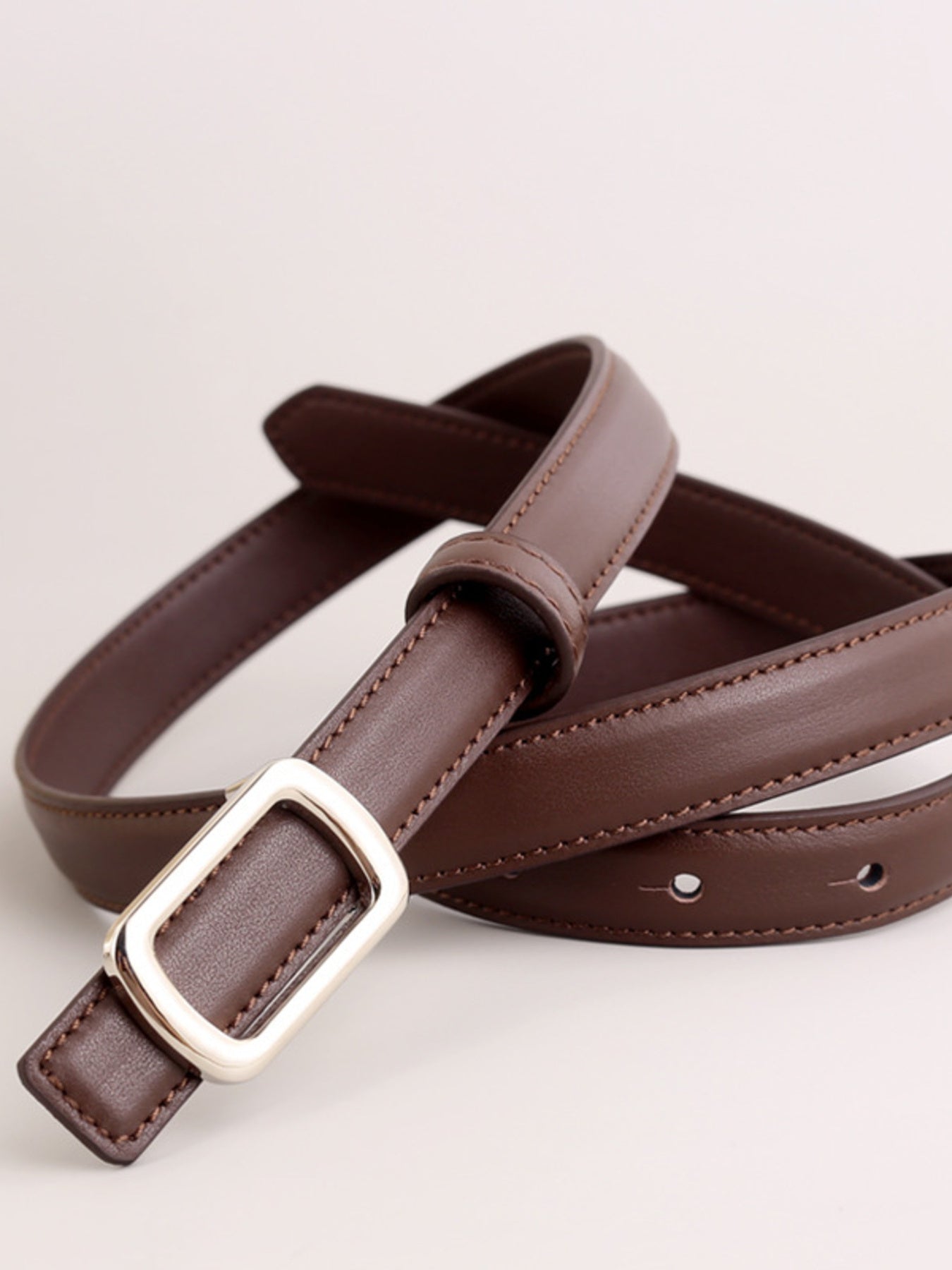 Brown leather skinny belt with silver buckle and stitching detail