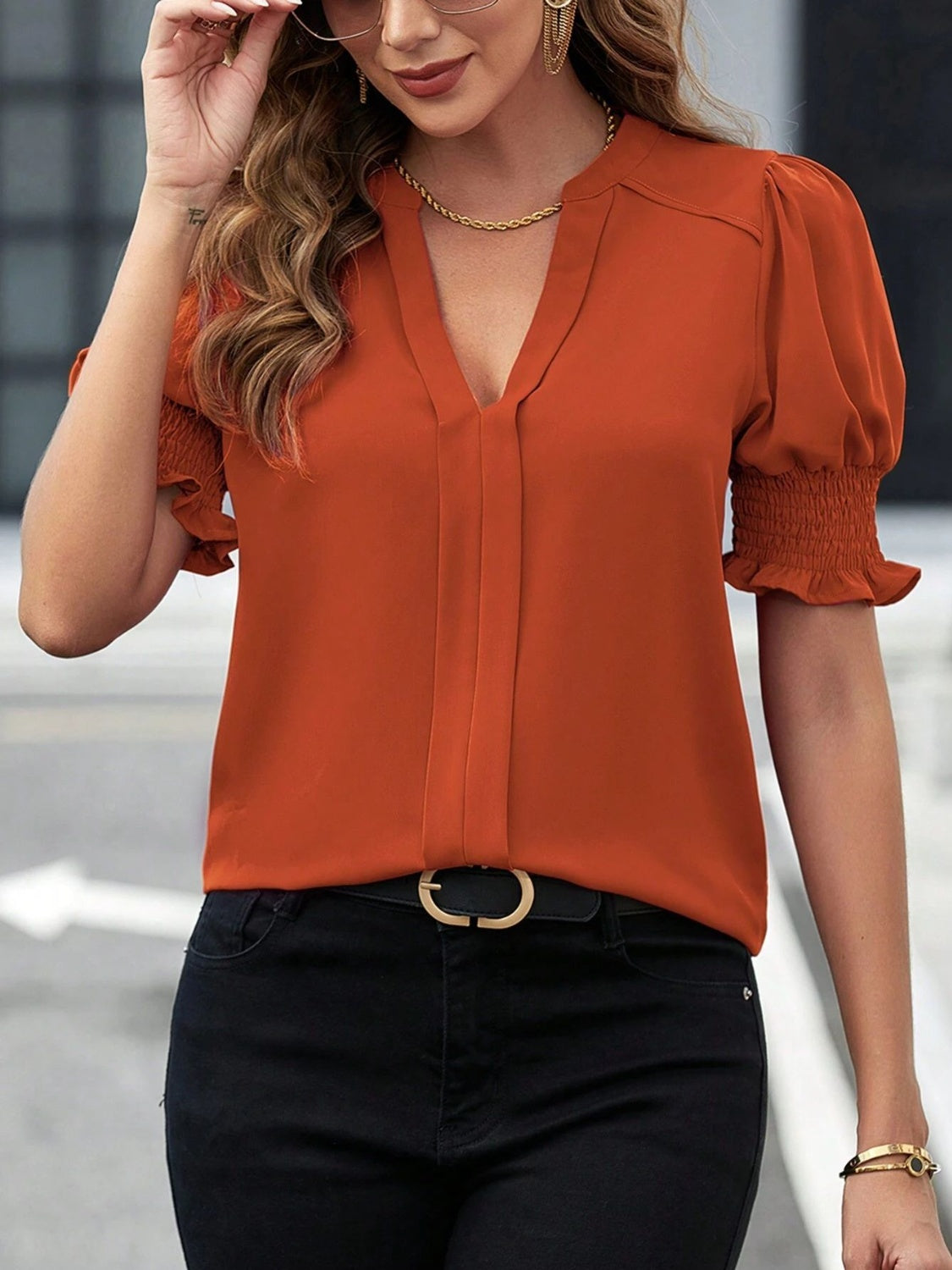 Orange shirred sleeve plunge neck blouse with v-neck and cinched cuffs.