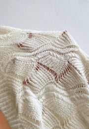 Ivory openwork knit V-neck pullover sweater with intricate stitch details.