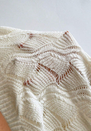 Ivory openwork knit V-neck pullover sweater with intricate stitch details.