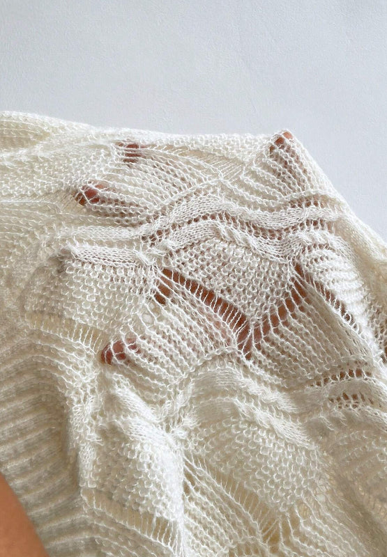 Ivory openwork knit V-neck pullover sweater with intricate stitch details.
