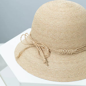 Woven straw bucket hat in Style B with a twisted band and bow detail.