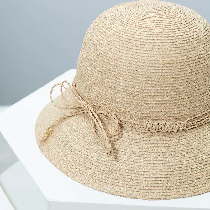 Woven straw bucket hat in Style B with a twisted band and bow detail.