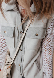 Light gray cotton utility vest with contrast trim and button-down pockets.