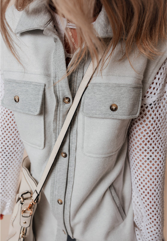 Light gray cotton utility vest with contrast trim and button-down pockets.