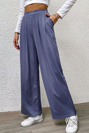 Steel wide-leg pleated front trousers with pockets, styled casually with sneakers.