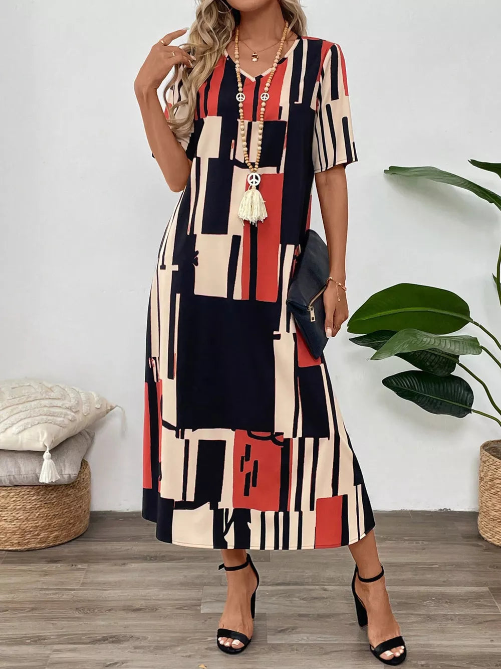 Geometric V-neck midi dress in dark blue, red, and cream abstract print.