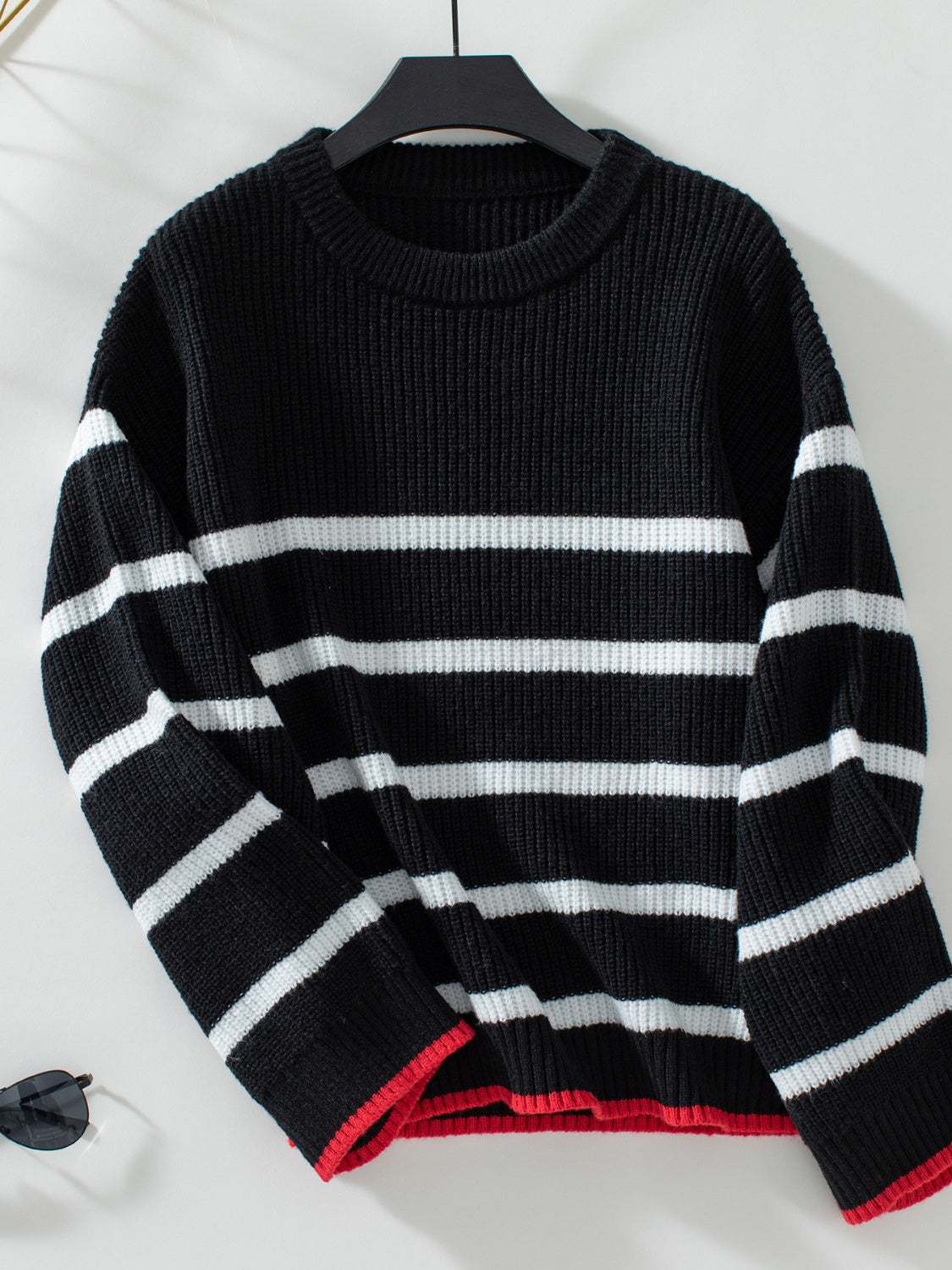 Black ribbed knit sweater with white stripes and red trim detail.