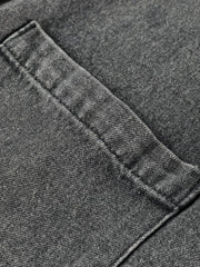 Faded gray denim pinafore dress detail showing a pocket with visible stitching.