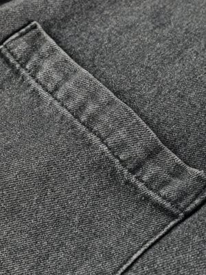 Faded gray denim pinafore dress detail showing a pocket with visible stitching.