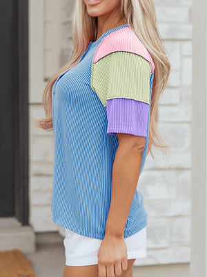 Color block patchwork henley t-shirt with blue stripes and pink, green, and purple sleeves.