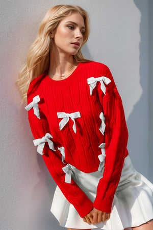 Red cable knit sweater with white bow embellishments and crew neck.