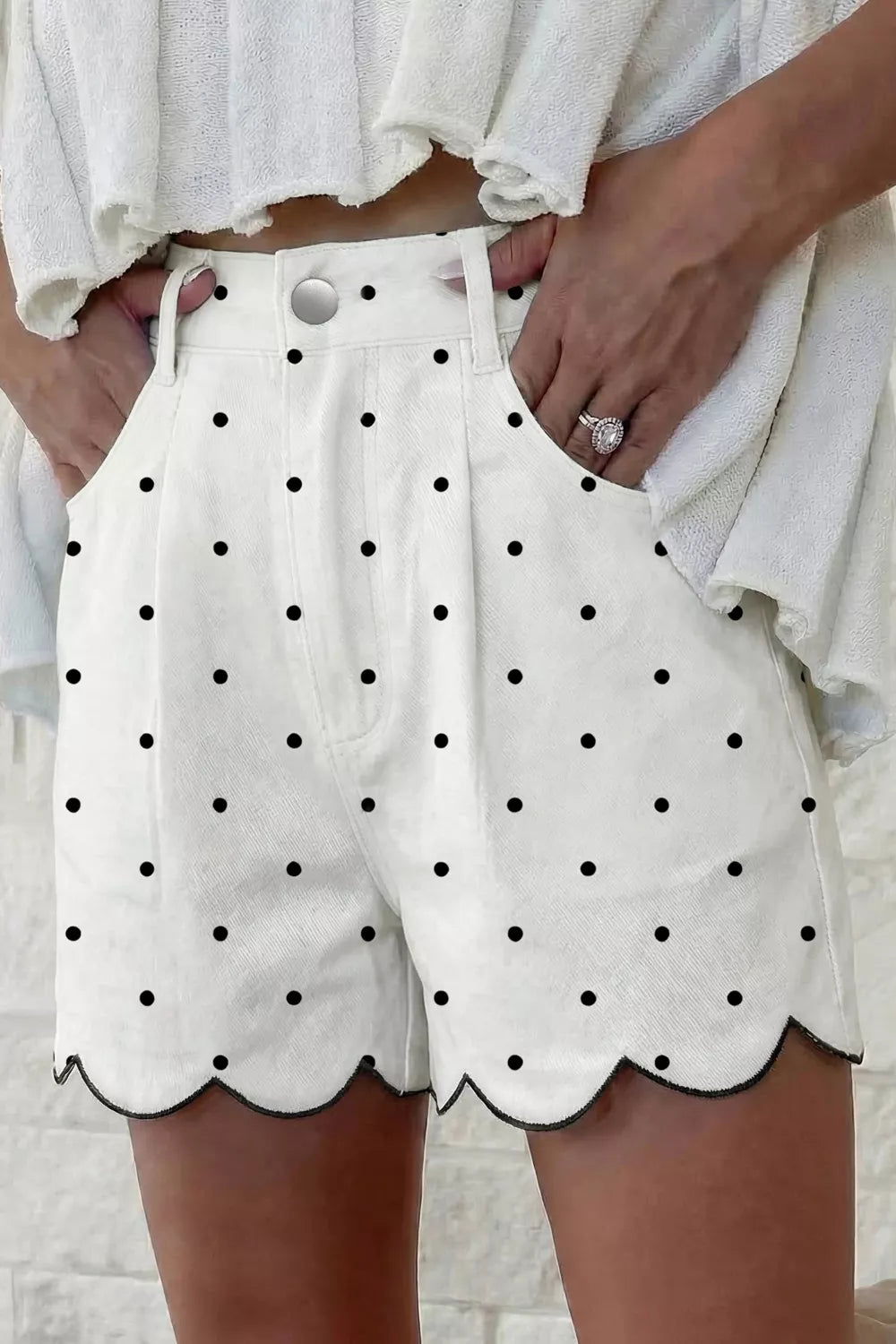 White chino shorts with black polka dots and scalloped hem detail.
